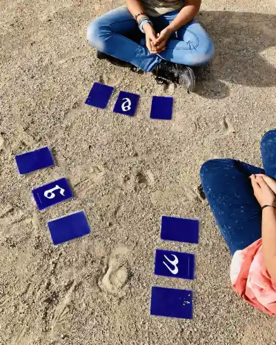 Drei Personen sitzen im Schneidersitz im Kreis mit je drei blauen Symbolkarten vor sich